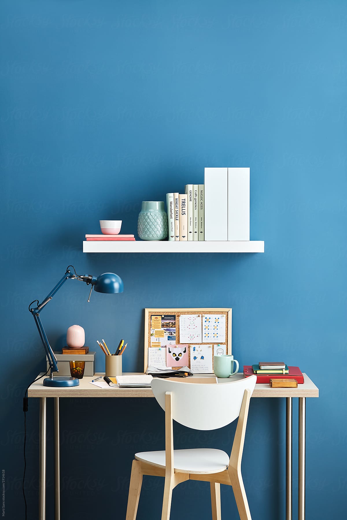 Desktop, chair and shelf over solid blue wall.