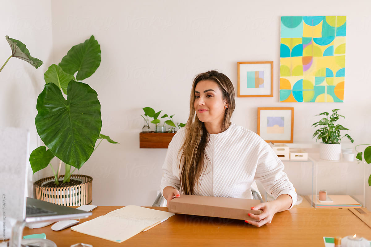 Pretty entrepreneur with shipping box at home office