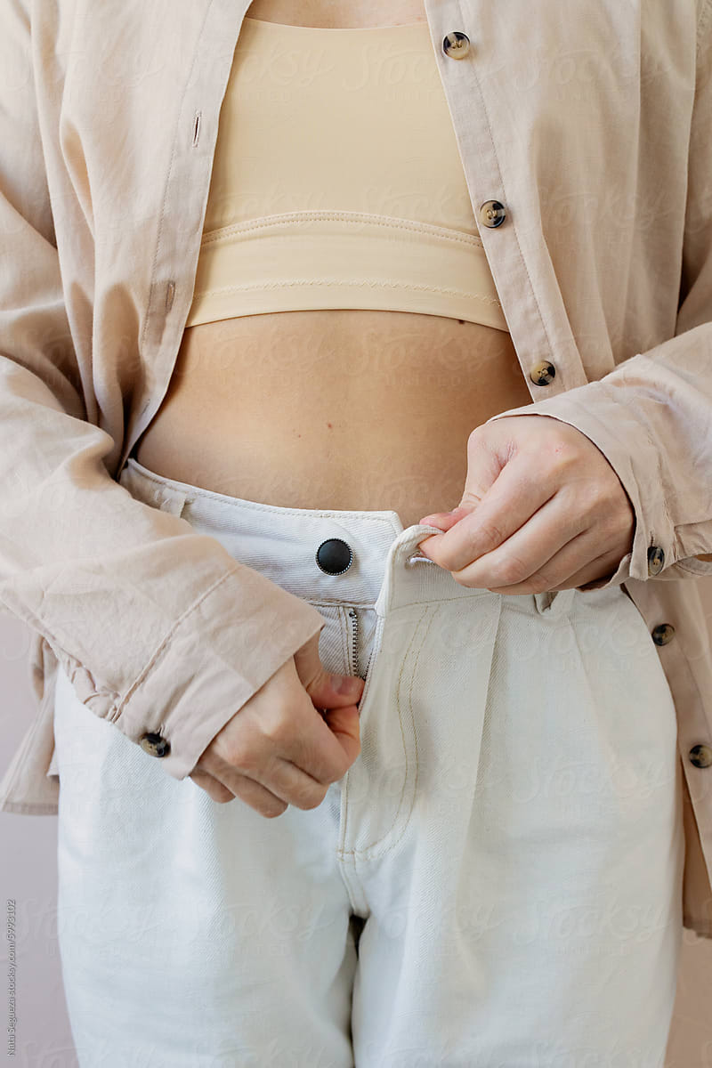 A woman zips up her pants.