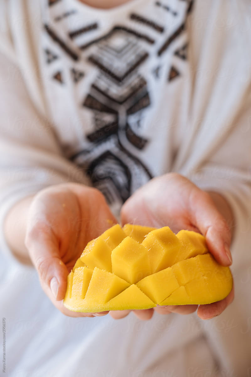 Unrecognizable woman holding half of cut mango