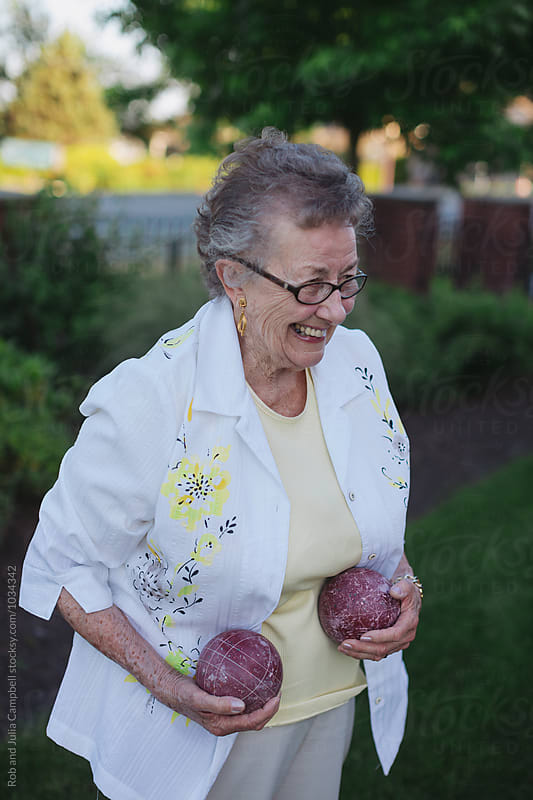 Healthy caucasian senior woman playing fun game of bocce ball outside