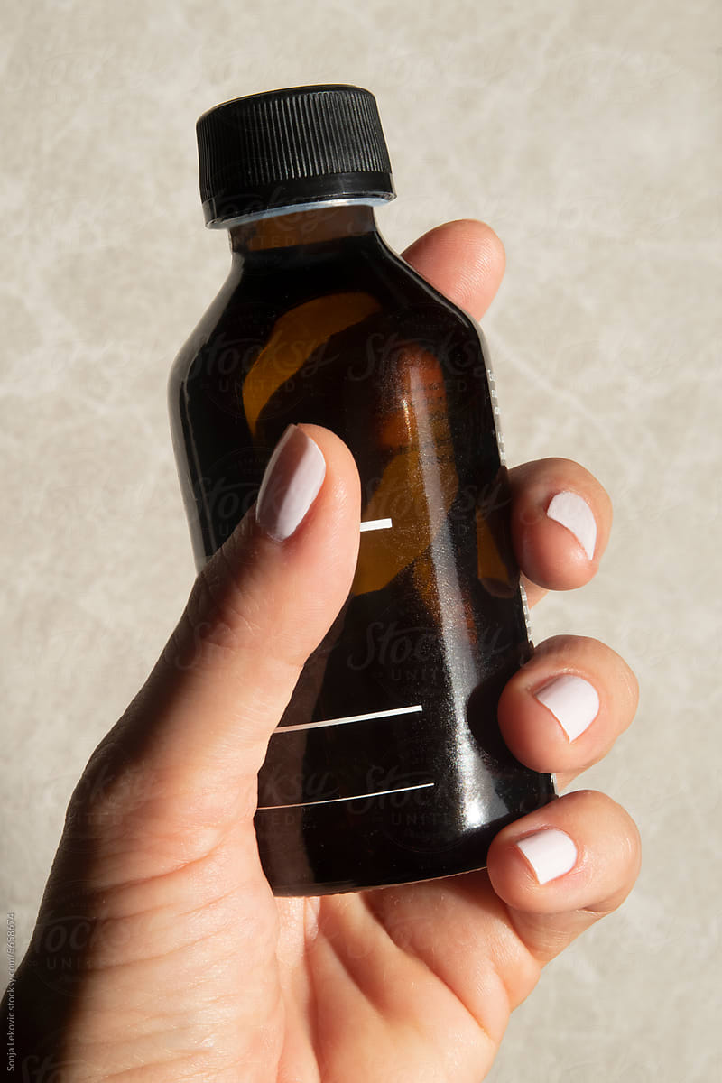 Cosmetics product in brown glass bottle in hand closeup