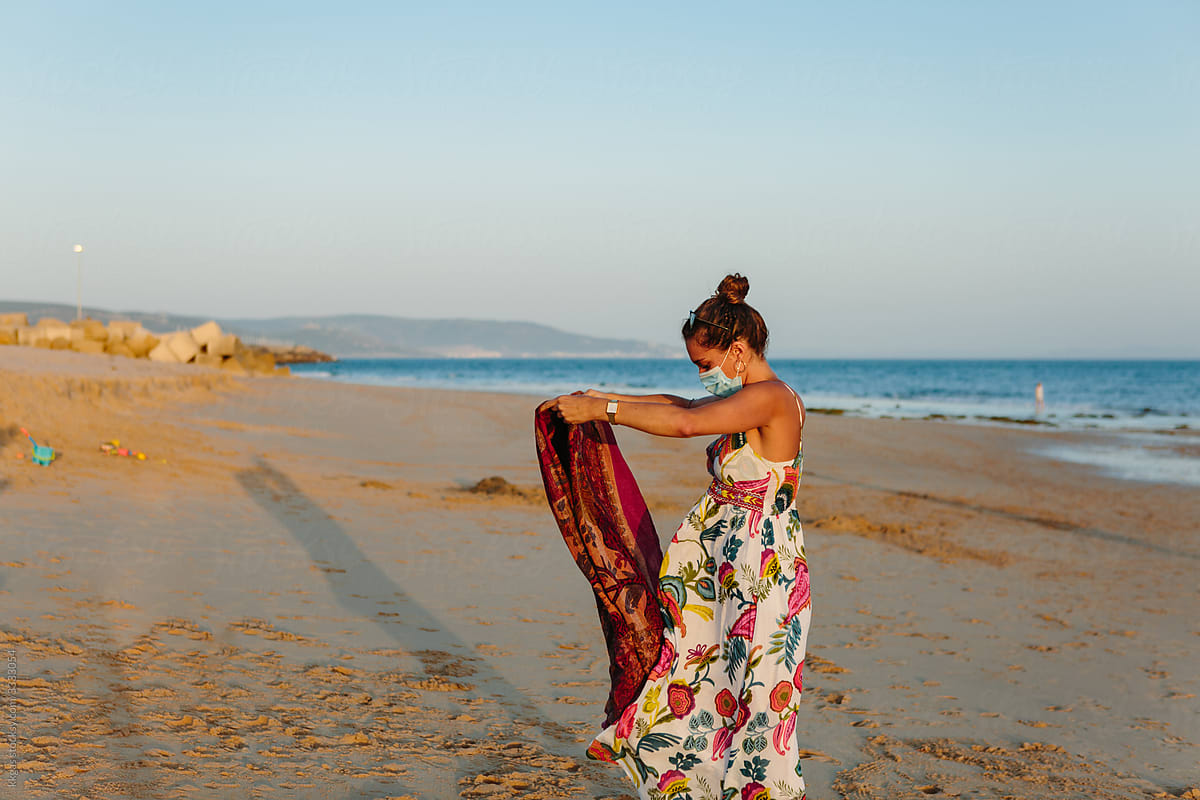 Woman in mask folding beach towel