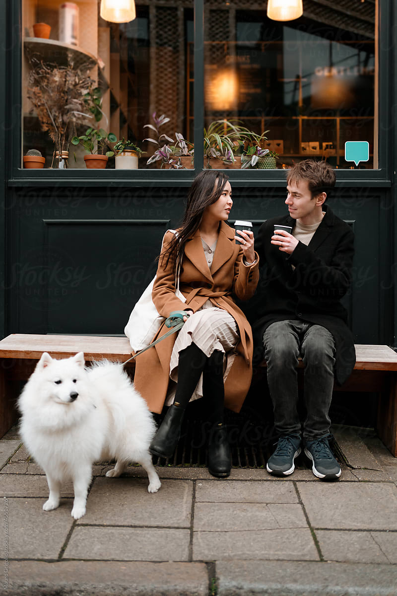 Two people with a dog are drinking a coffee out of a cafeteria