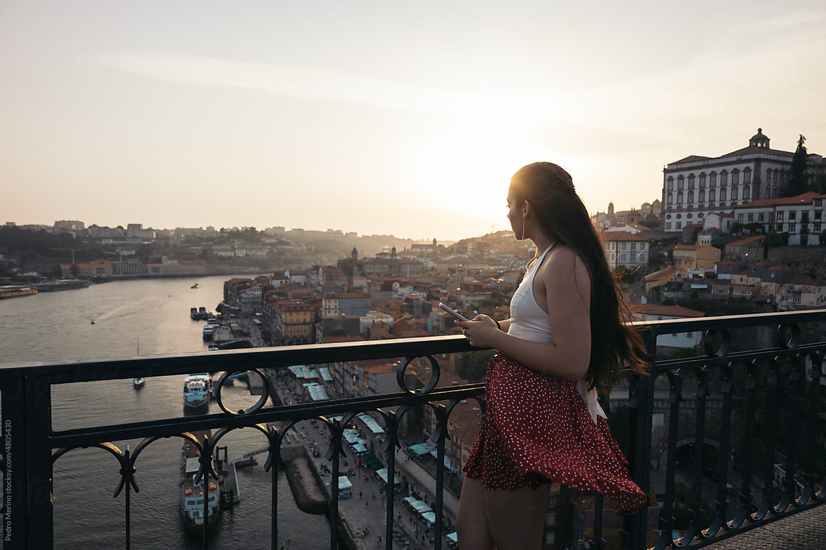 Young woman using smartphone and watching the city from the bridge