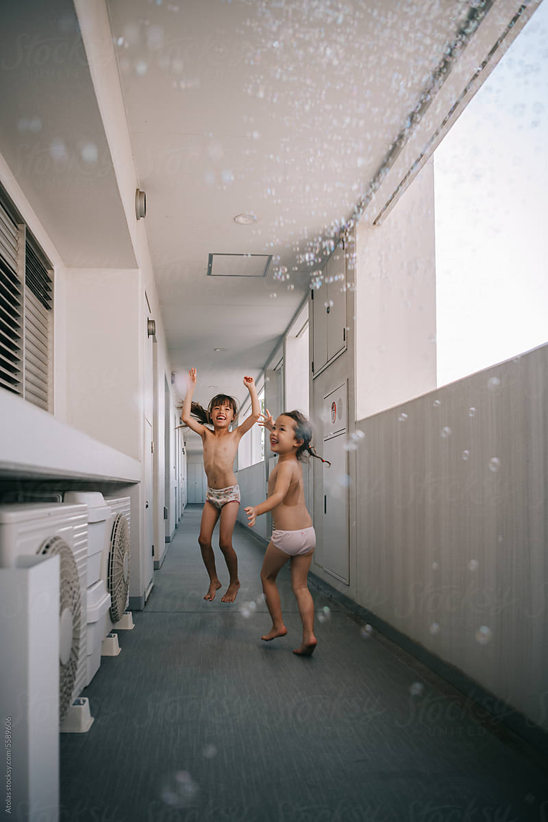 Little Sisters In Underwear Playing With Bubbles by Stocksy