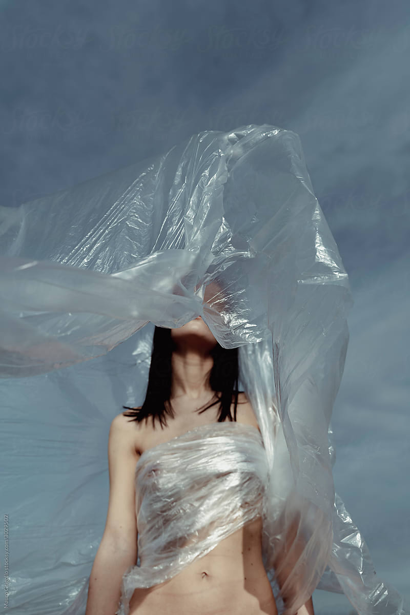 Nude woman in nature covered with plastic film