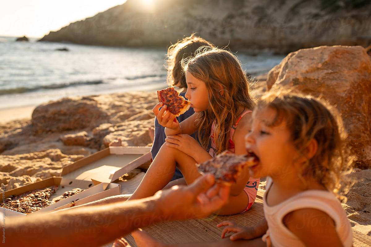 Kids eating pizza on the beach