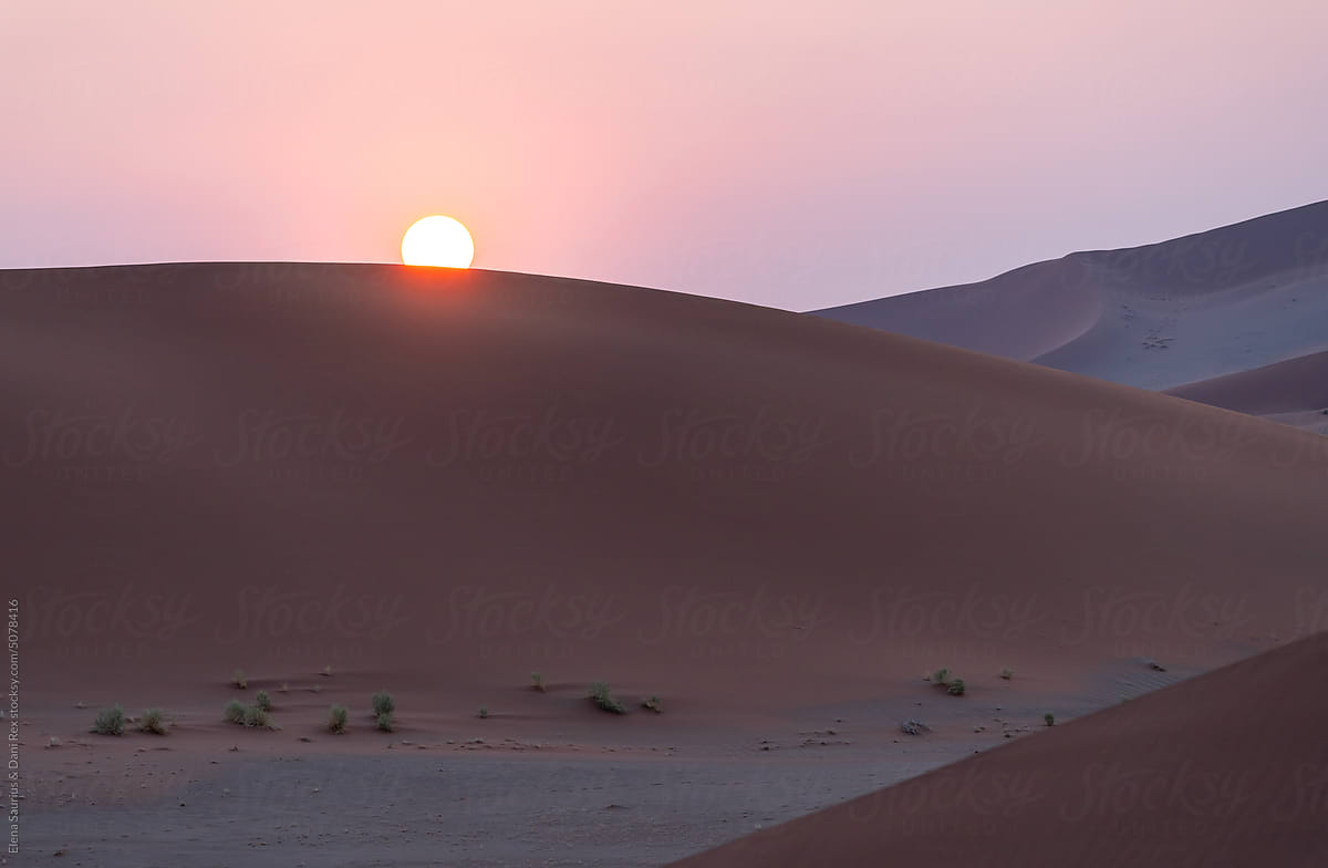 Sand dunes in front of the sun at sunset in Namibia, Africa.