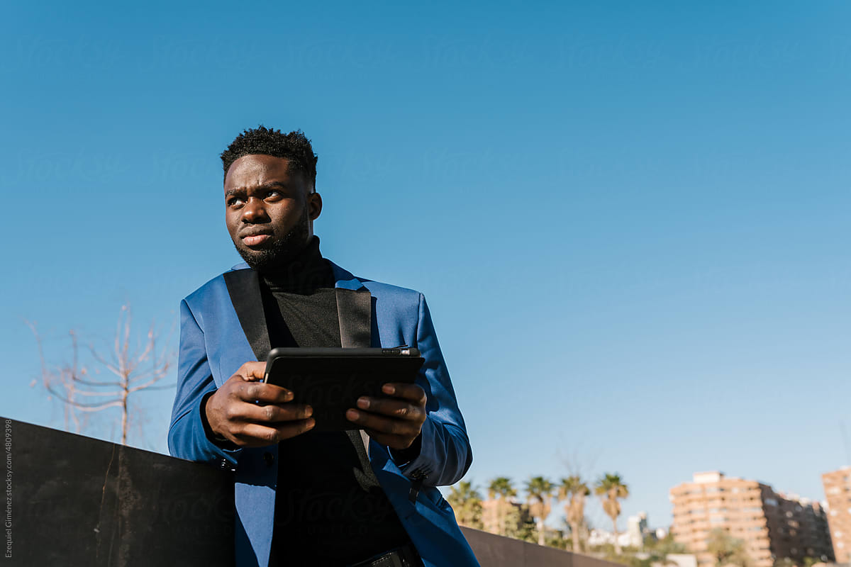 Confident black man browsing tablet on street