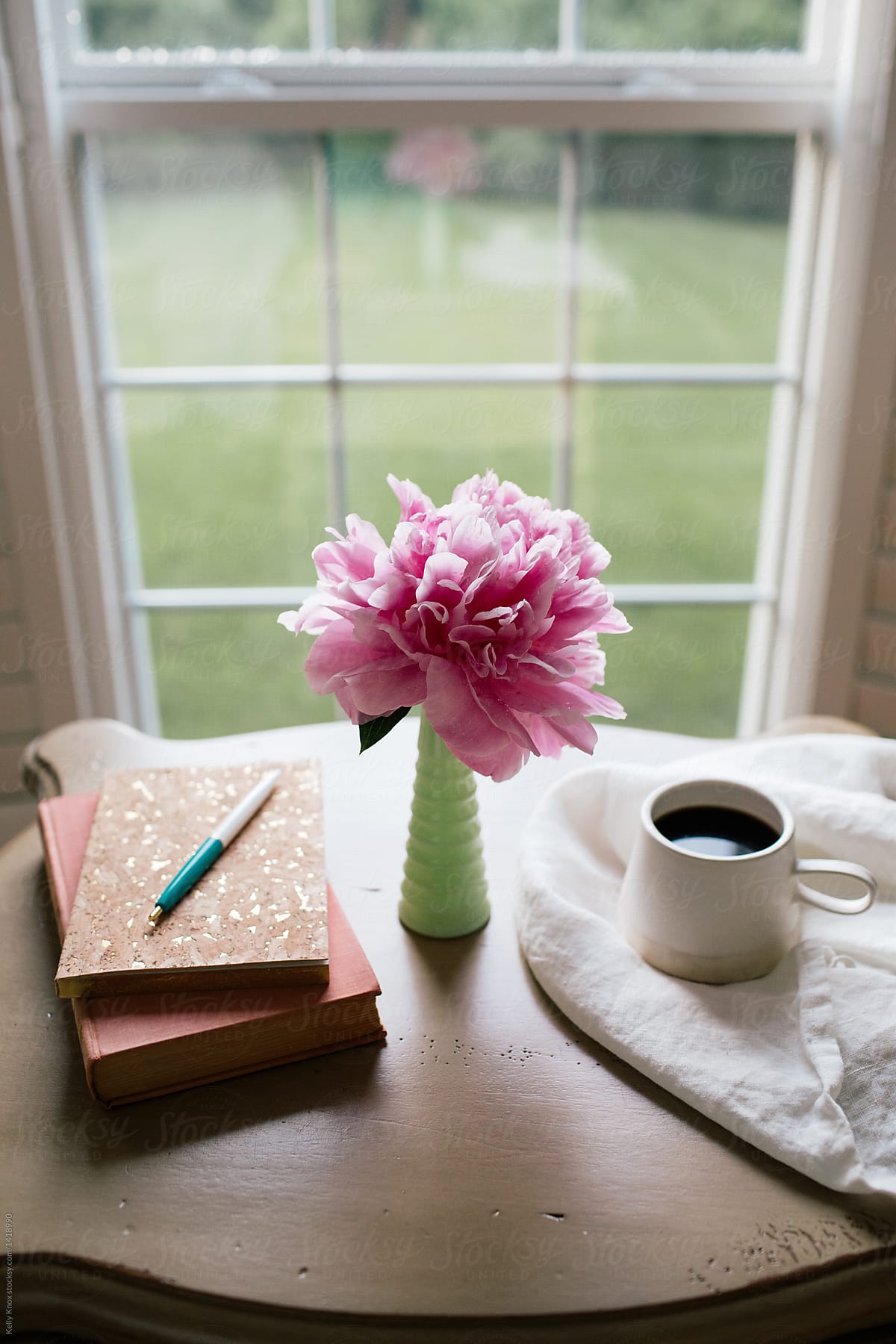 vertical image of a journal, book, coffee, and flower on a desk by