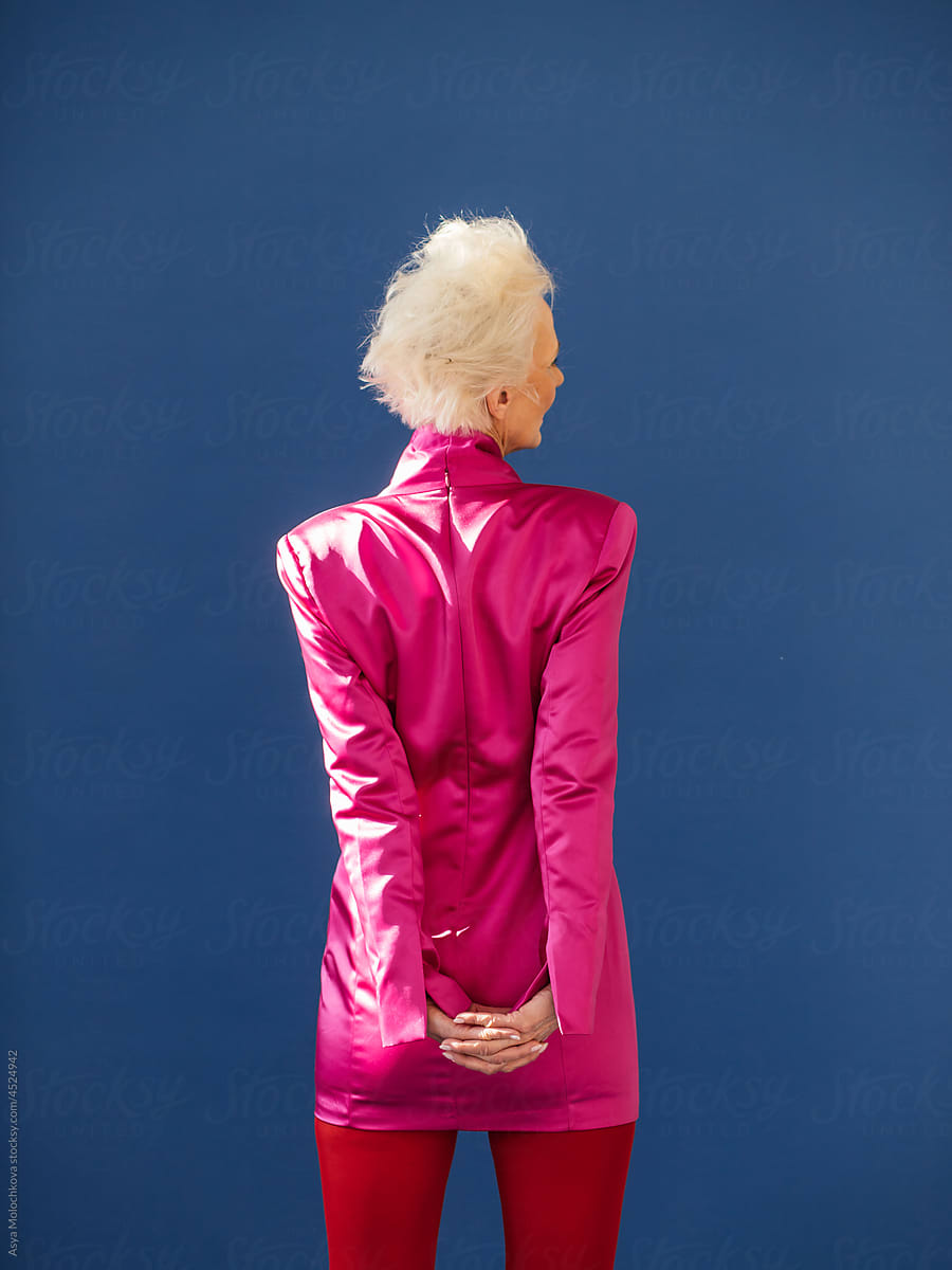 Unrecognizable elderly woman standing back on blue background
