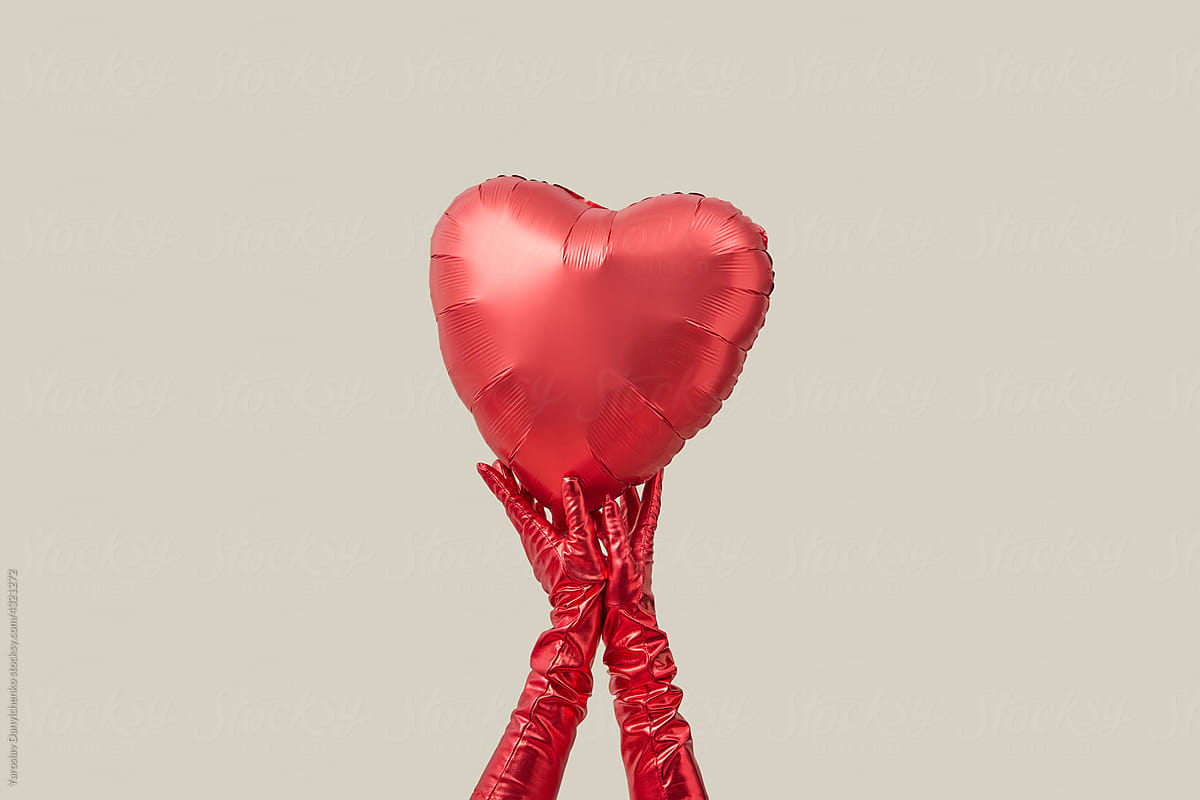 Woman in red gloves holding balloon in shape of heart