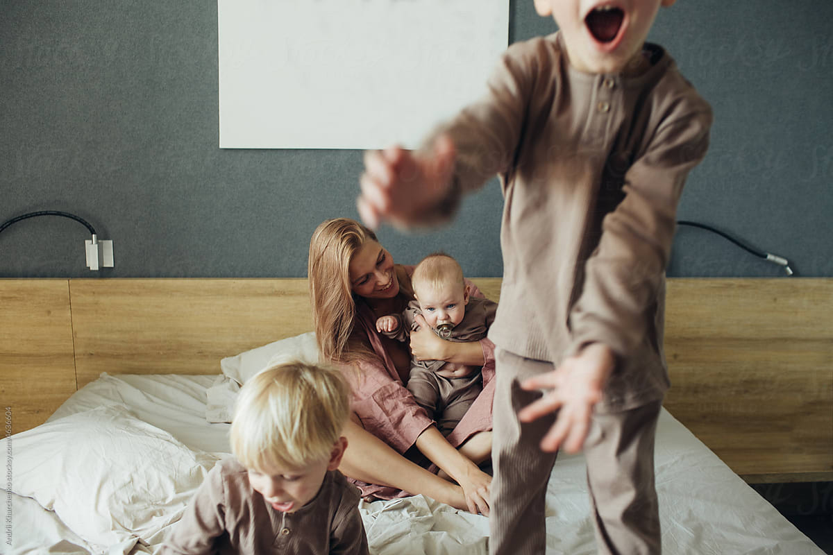 Mother with three little sons woke up and have fun on the bed