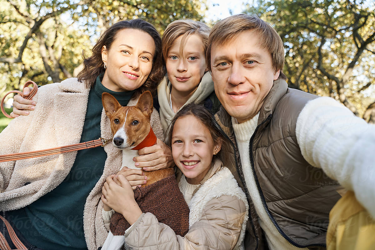Family with dog taking selfie in park