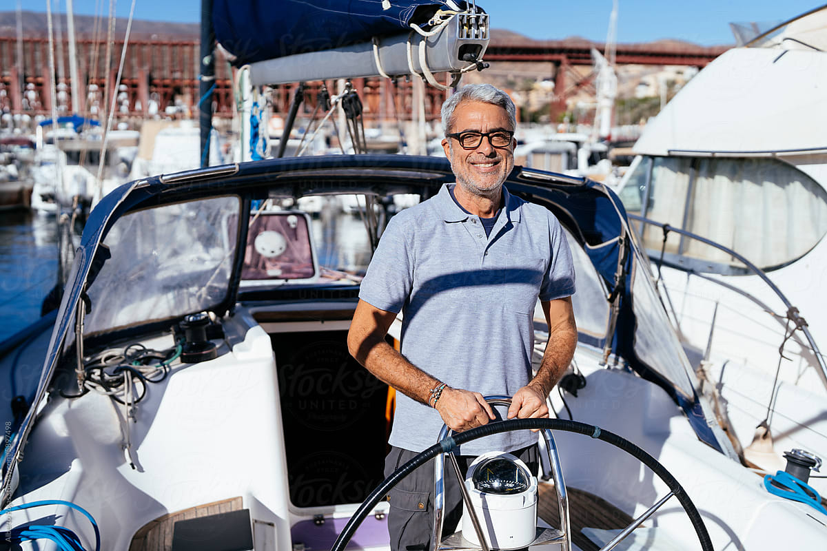 Positive senior captain standing in helm of sailboat
