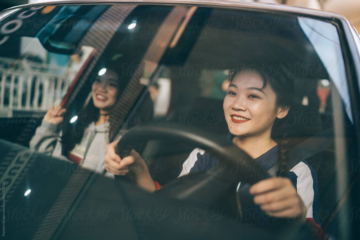 two young female friends drive in city
