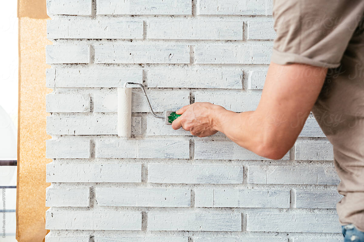 Man with roller painting brick wall