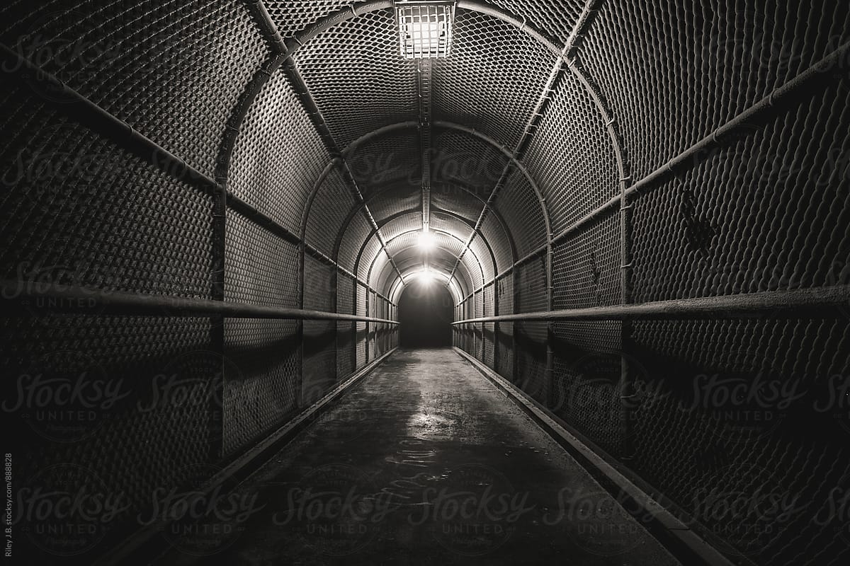 A cold, dark, fenced walkway leads to darkness.