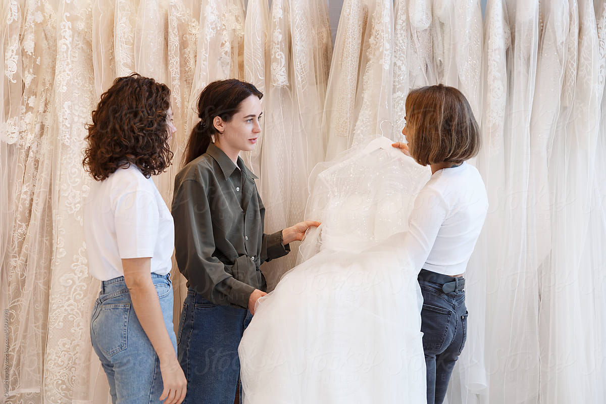 Women buying wedding gown from shop owner