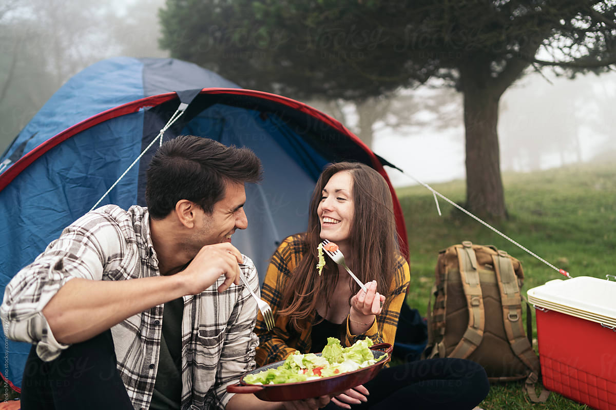 Couple eating outdoors while camping in the woods