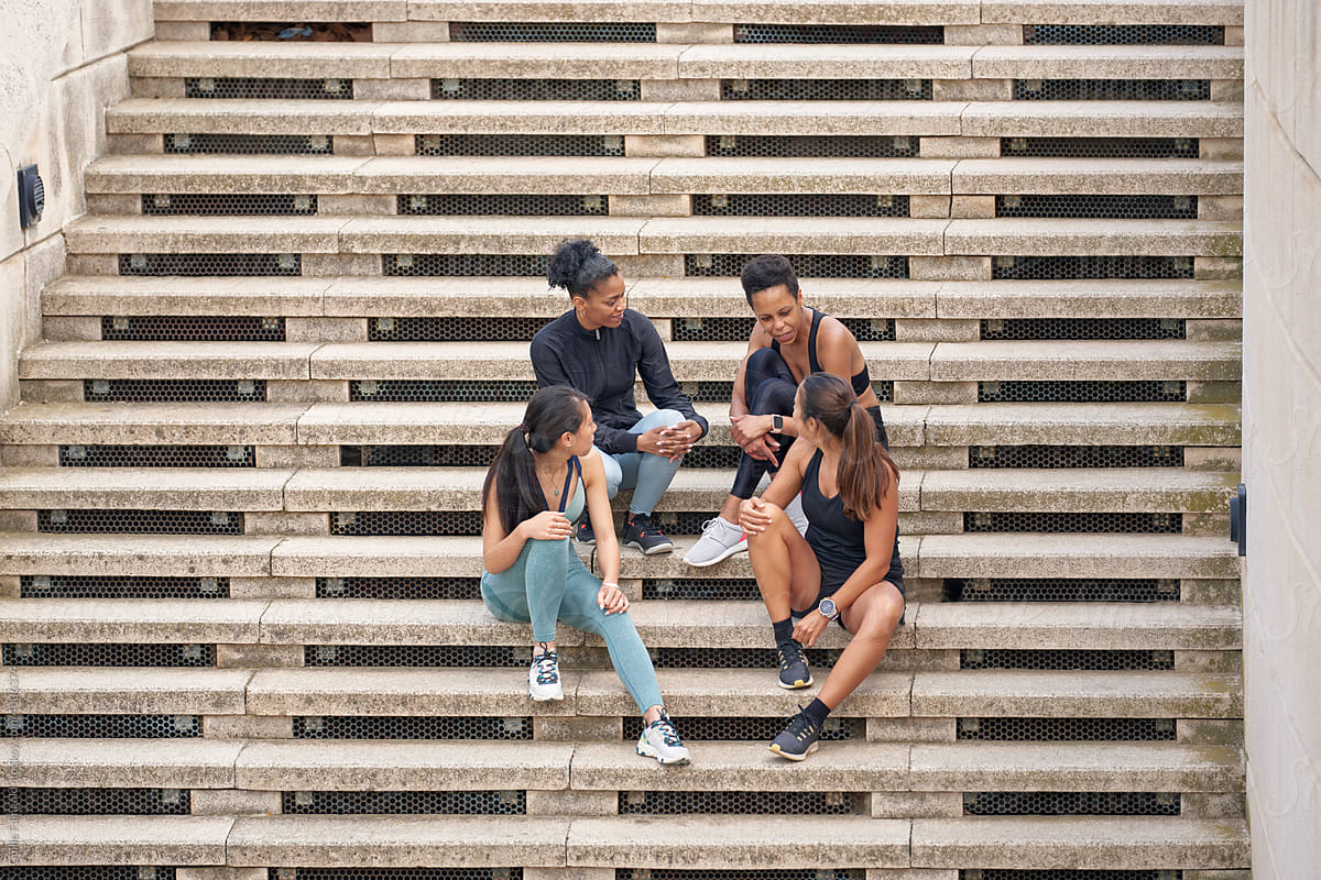 Female joggers sitting on staircase and chatting