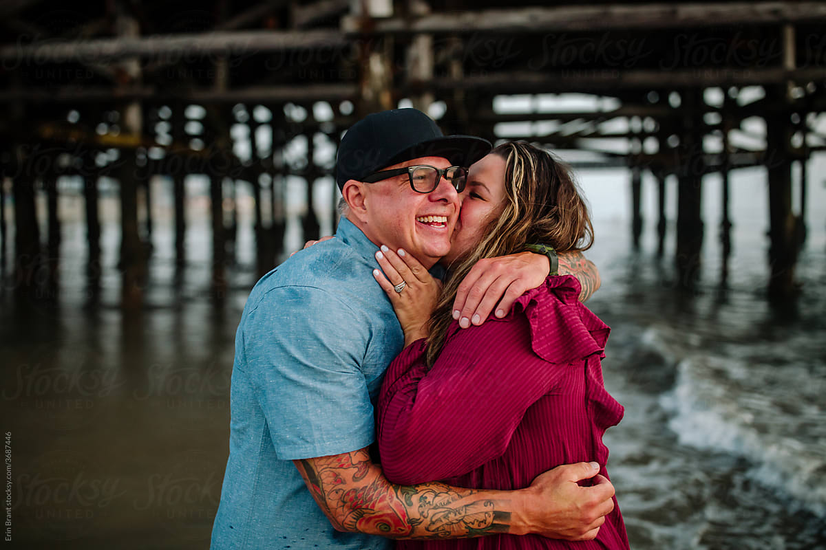 Joyful wife kisses husband under pier