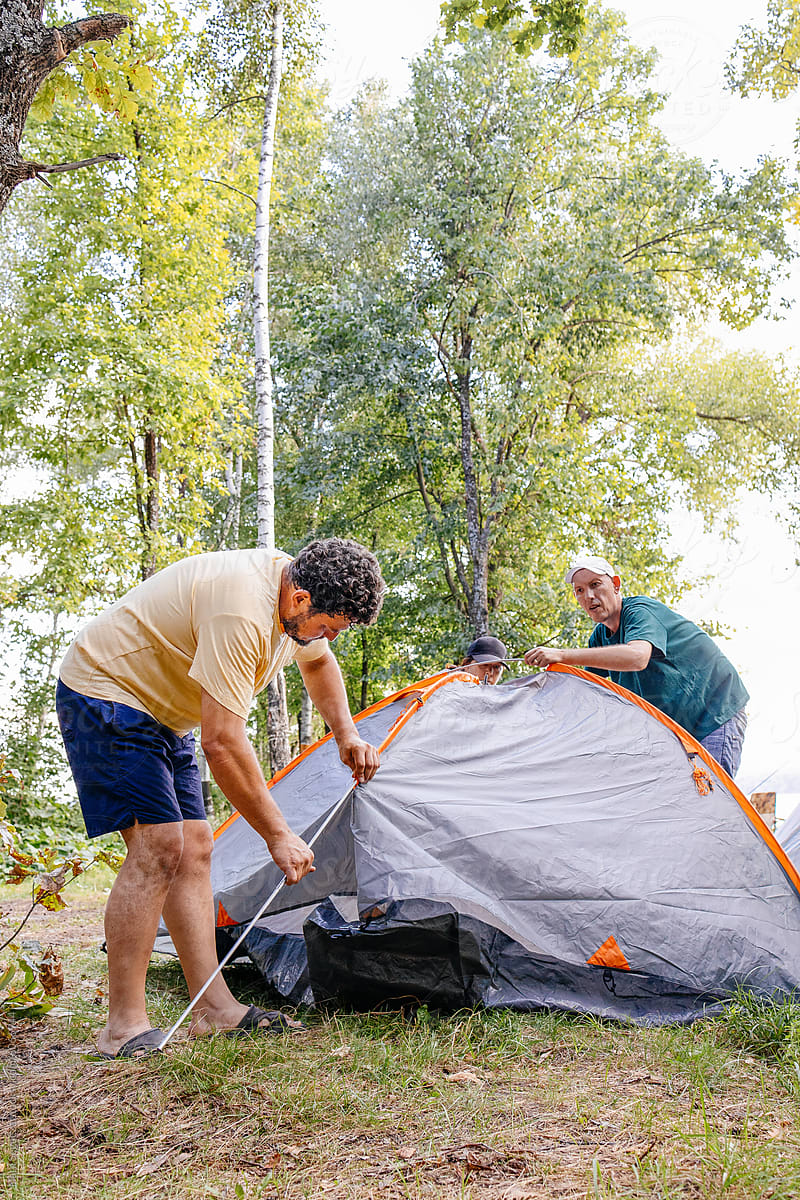 Friends Setting Up Tent by Lake at Daytime