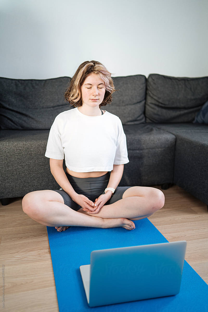 Young woman meditating in front of laptop