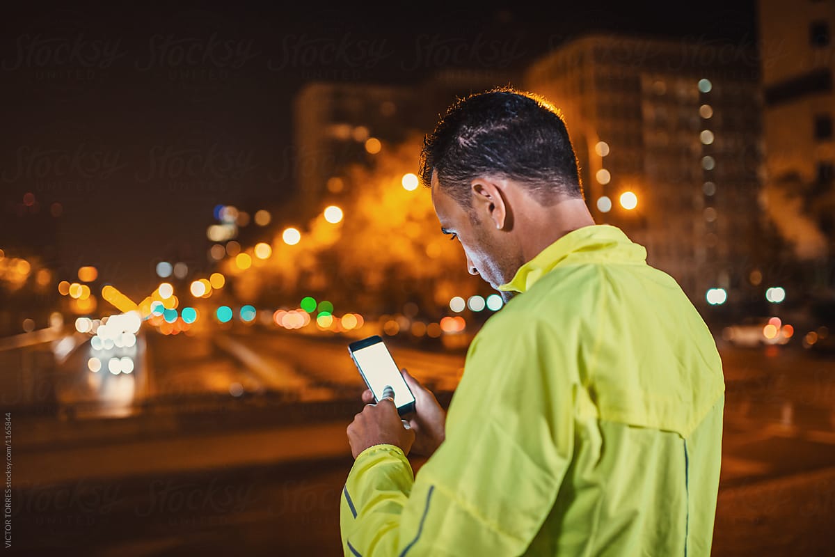 Sportsman in yellow using mobile phone at night