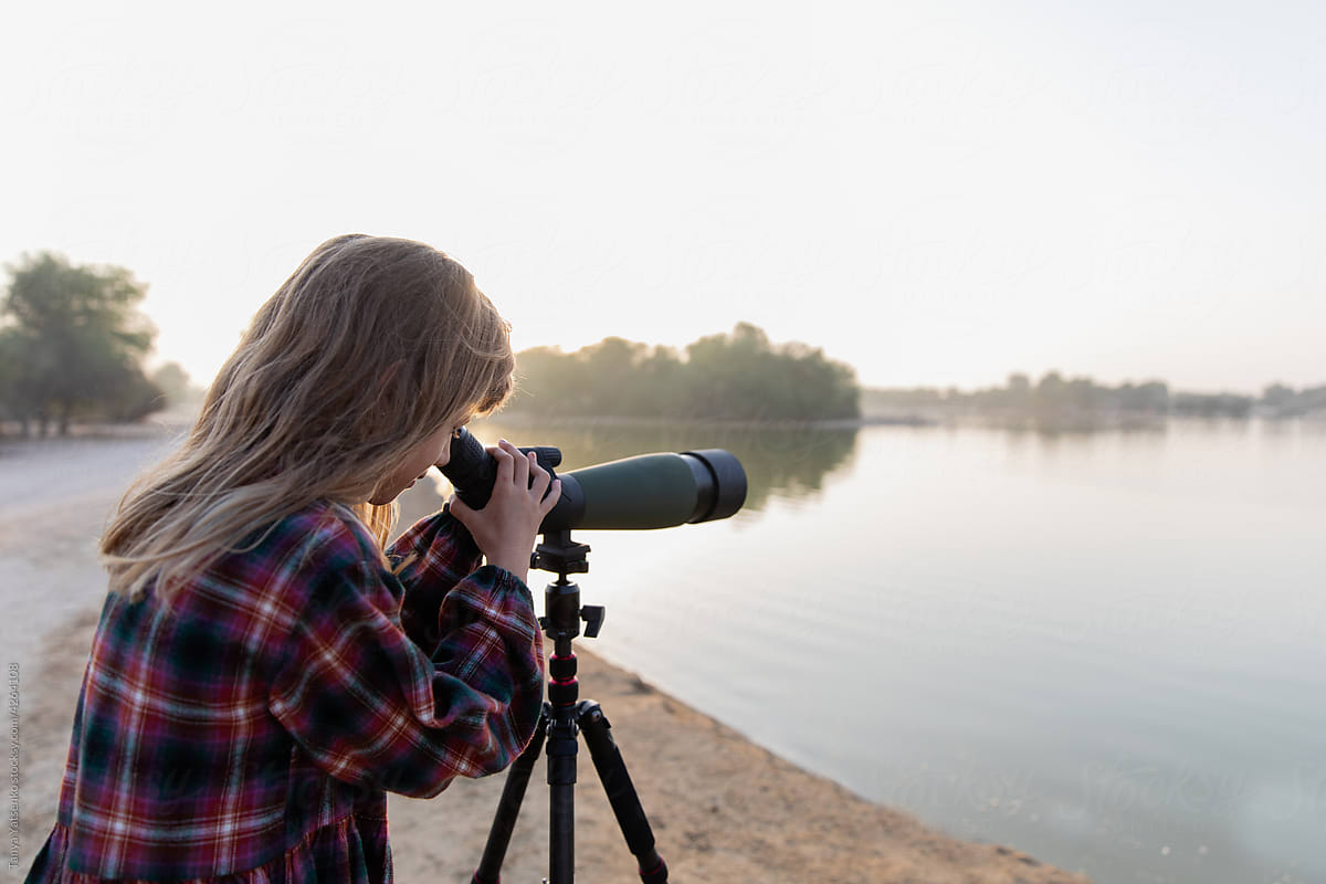A girl is looking at the birds through a telescope