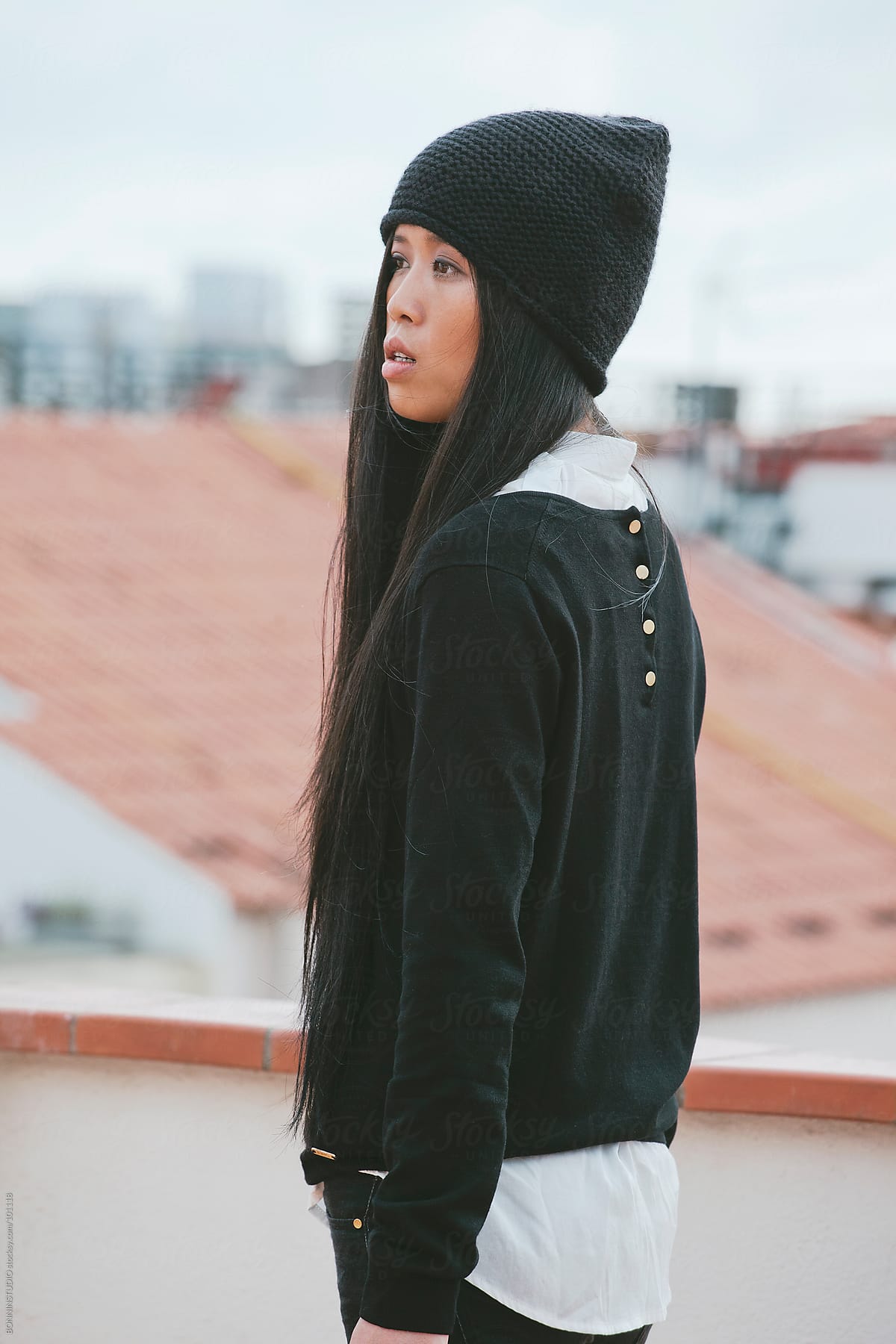 Young chinese woman standing on a terrace overlooking the city.