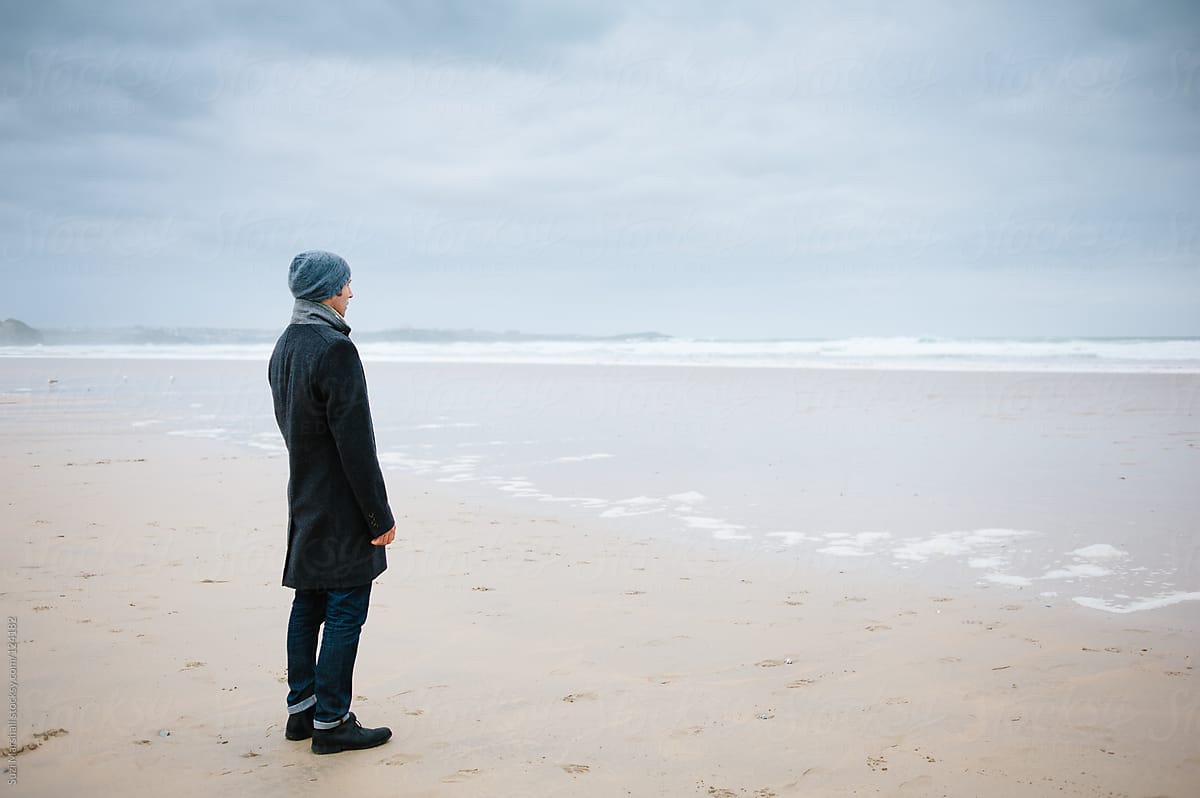 Man Standing Alone On The Beach Looking Out To Sea by Stocksy Contributor  Suzi Marshall - Stocksy