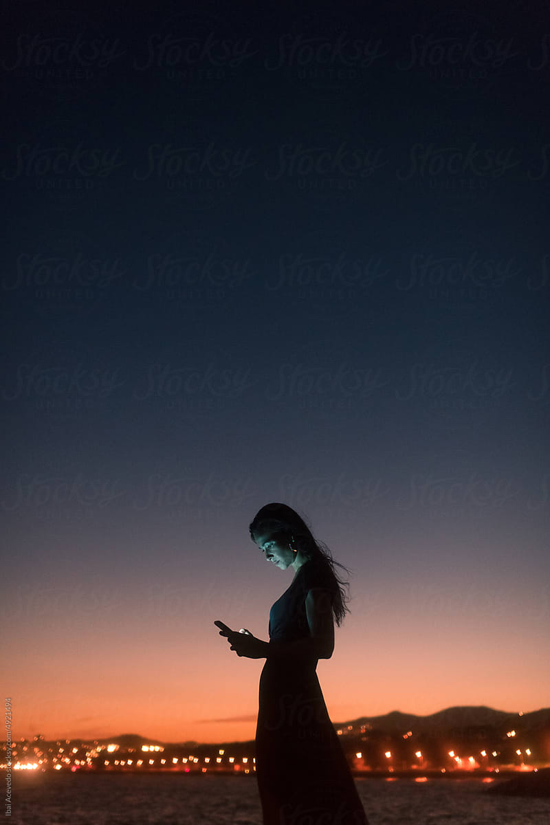 Relaxed woman texting on her phone at sunset