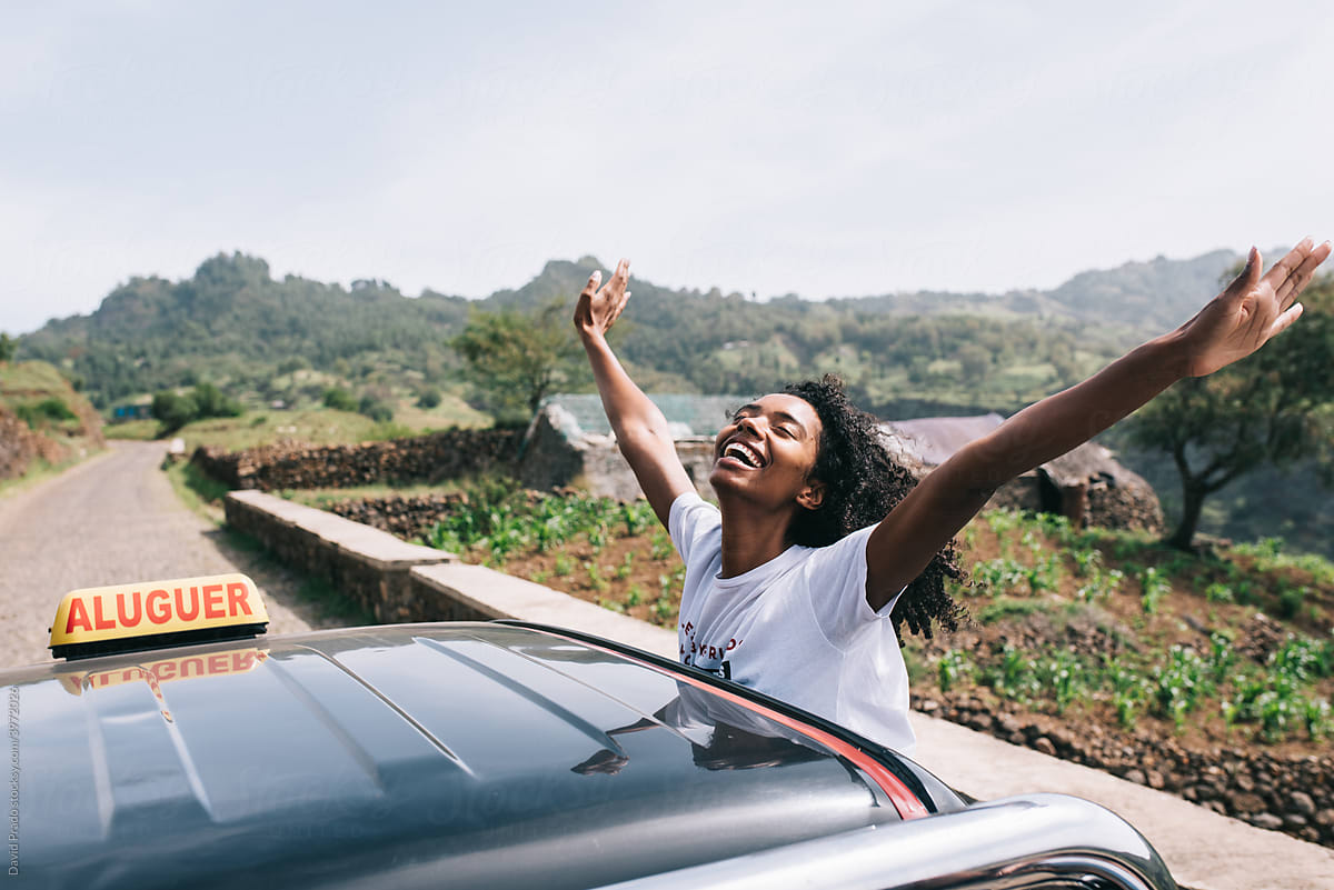 Happy ethnic female leaning out of car