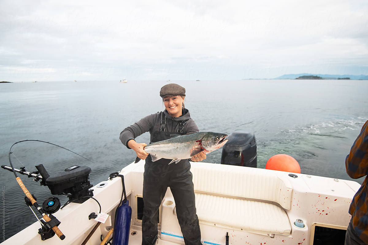 Woman holding a fresh salmon on a boat in the ocean