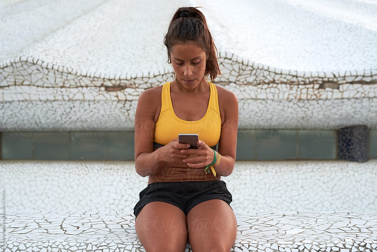 Sportswoman using smartphone outside mosaic building