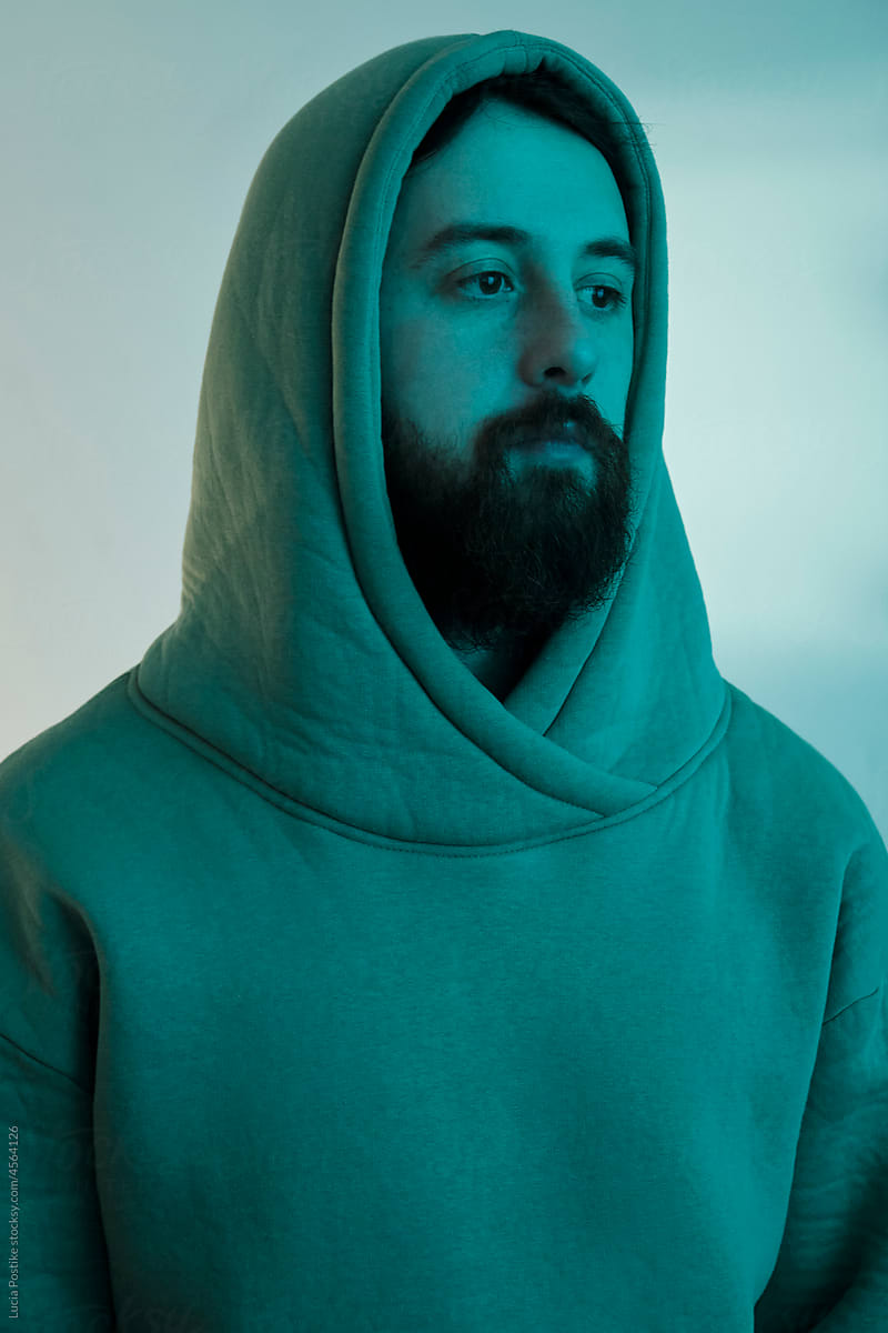 Man in a hood and with a beard in blue light