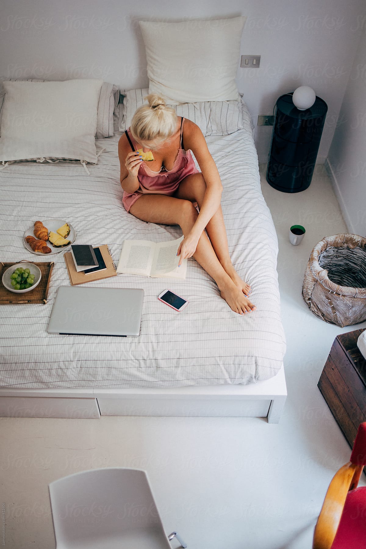 Woman Reading a Book and Having Breakfast in Bed