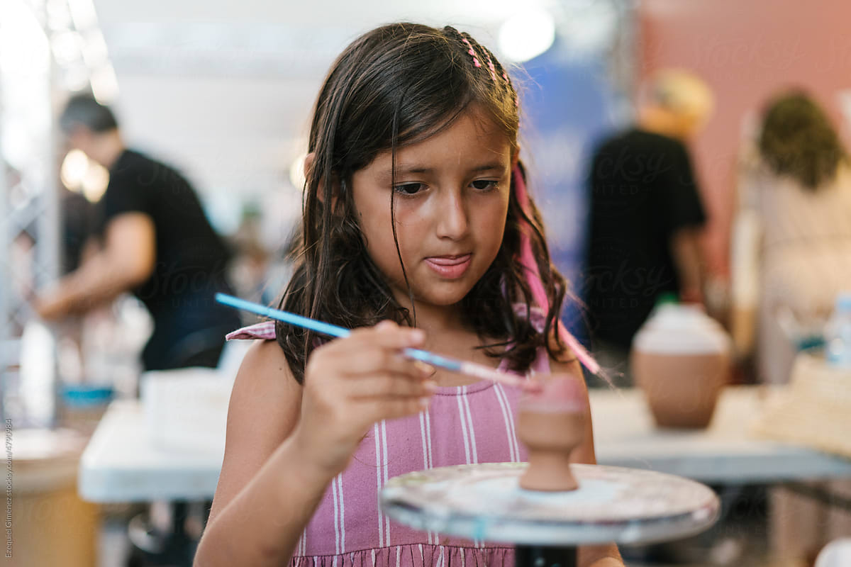 Focused girl painting on pottery in workshop
