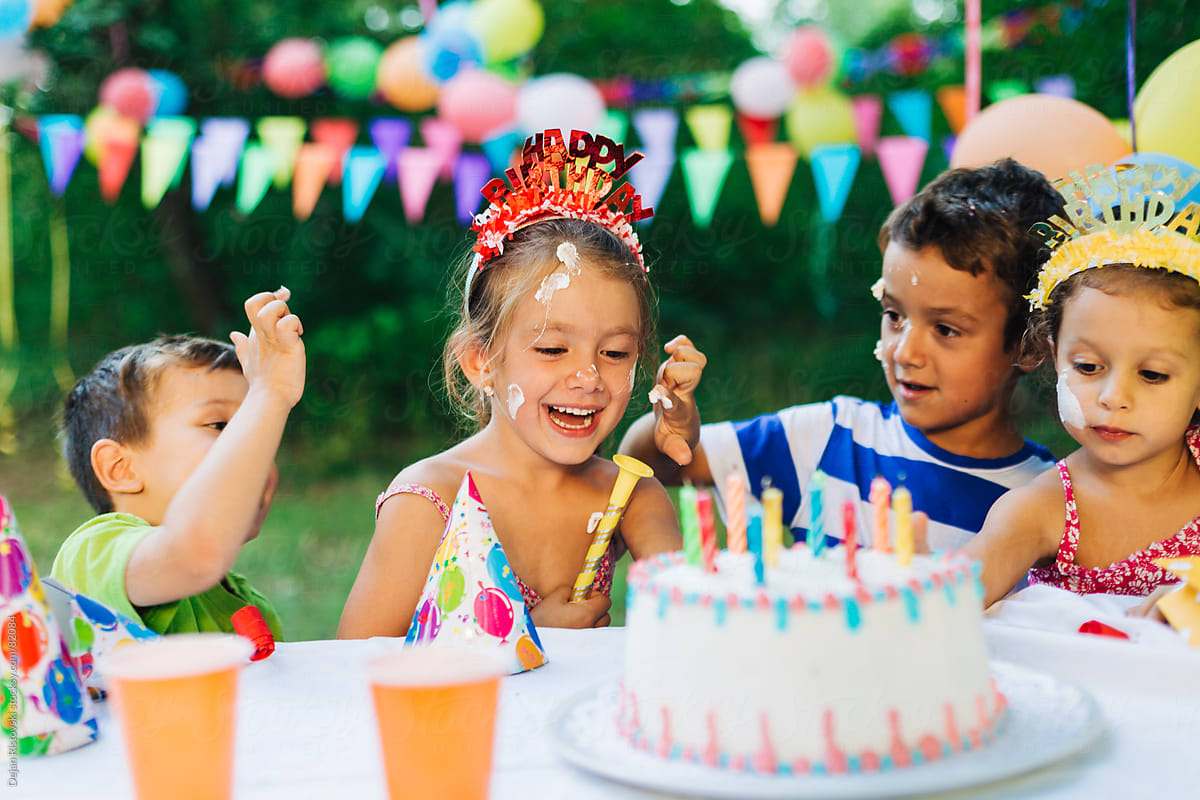 Children having fun with cake cream on a birthday party