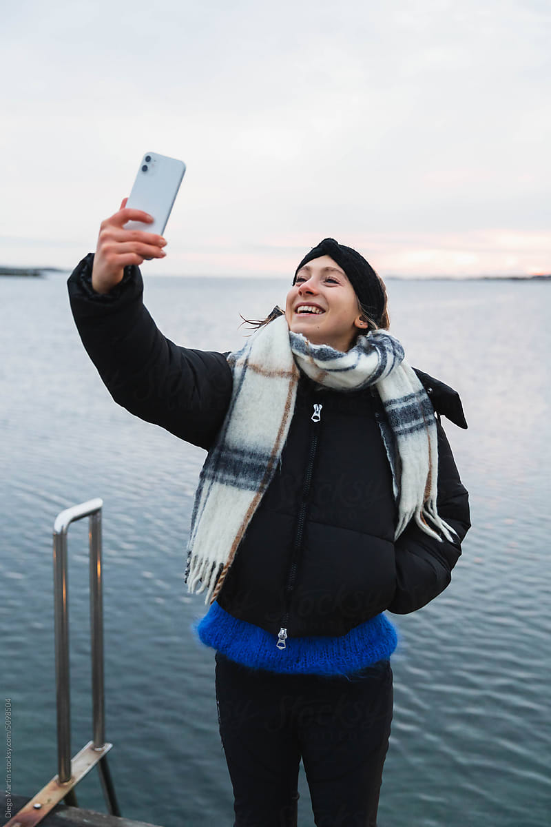 Young woman taking a selfie with her phone outside a cold day
