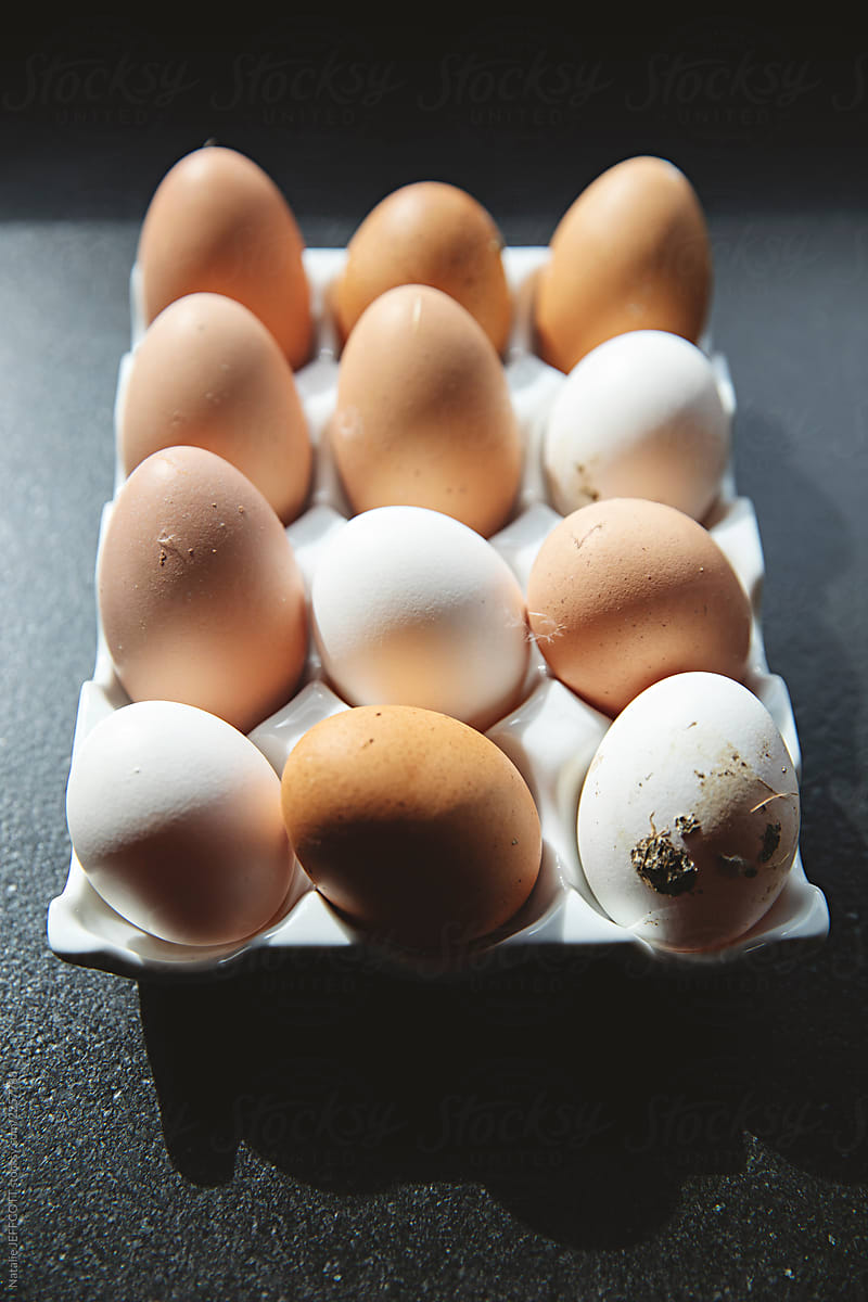 close up of freshly laid chicken eggs on black counter