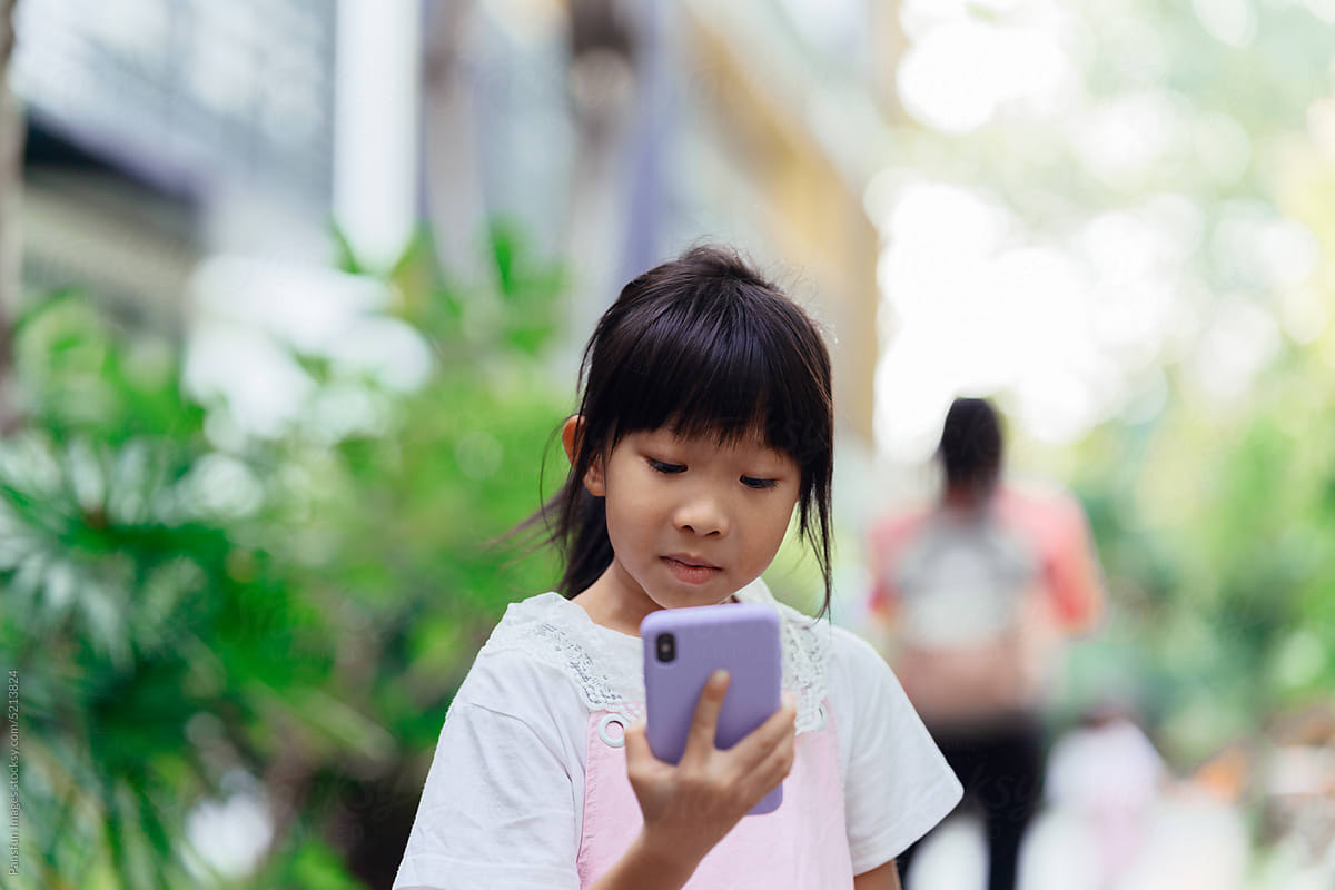 Little girl uses mobile phone navigation on the street