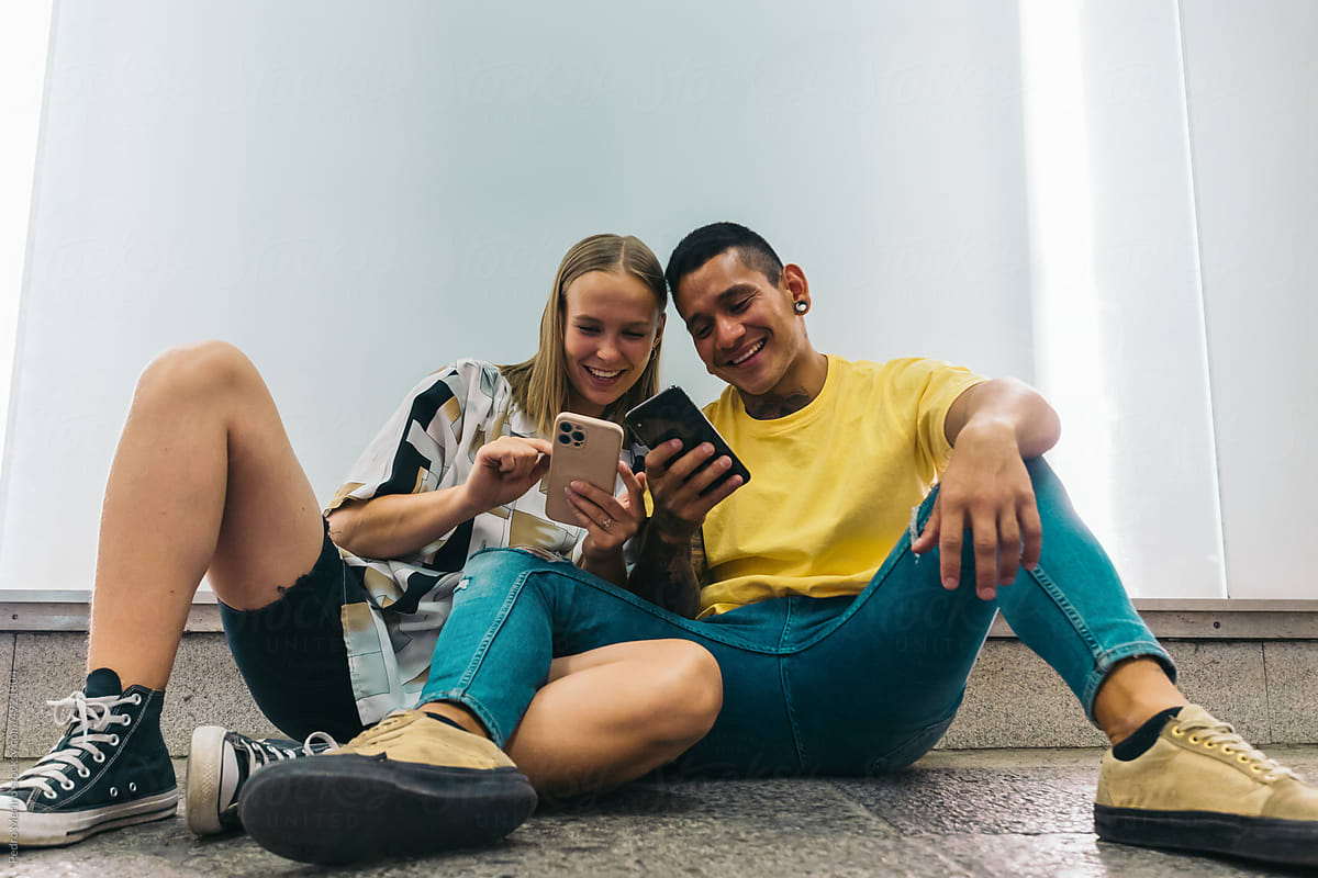 Stylish young couple using smartphone and having fun together