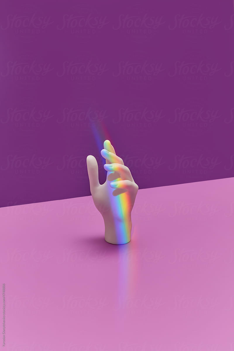 White hand with rainbow on purple background.