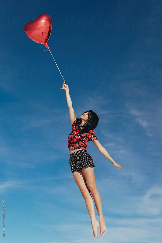 Beautiful woman flying away on a heart balloon on Valentine\'s Day