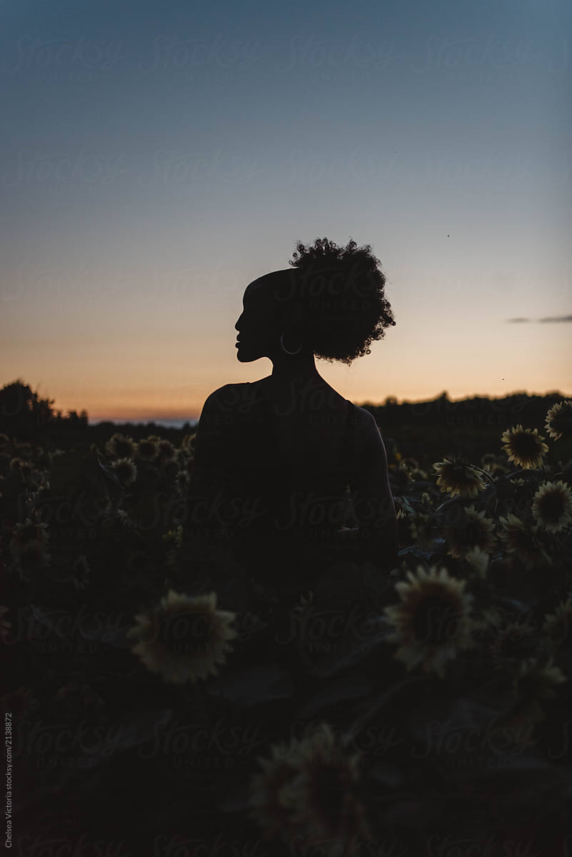 A Young African American Woman In A Sunflower Field At Sunset By