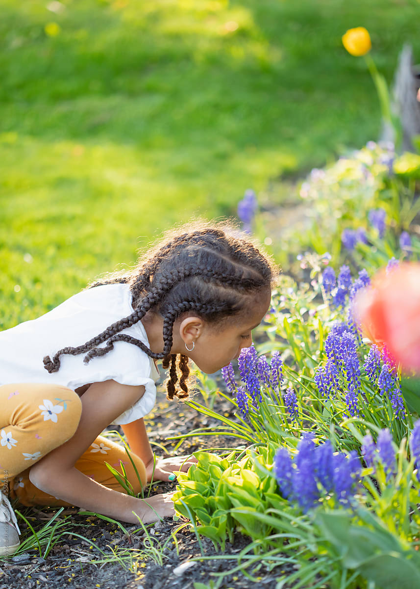 Cute child smelling a tulip in a spring garden