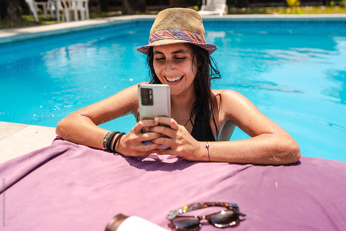 woman using her phone at a swimming pool